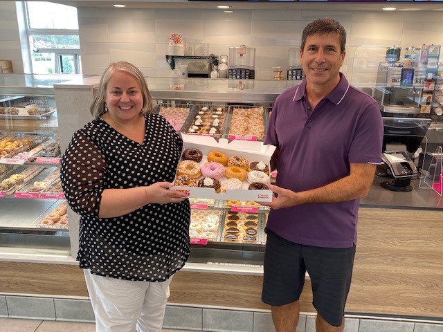 Dunkin’ franchisee Tom Santurri (right) celebrates the uapcoming National Donut Day by providing a box of donuts to Food Bank of Central New York Chief Development Officer Lynn Hy (left).